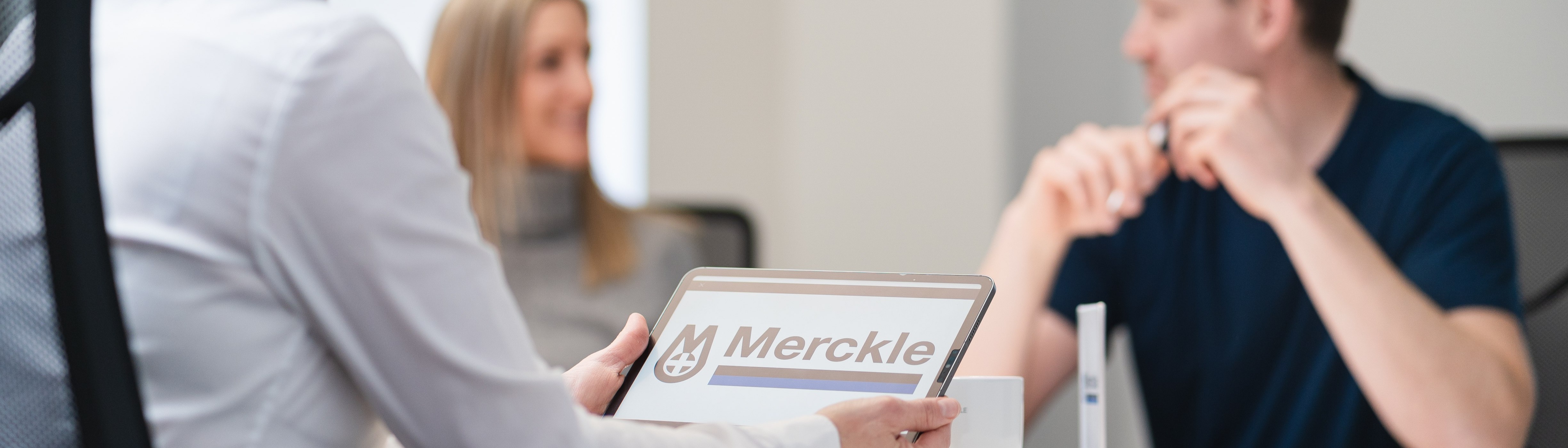 Merckle Service Logo und Mitarbeitende im Büro